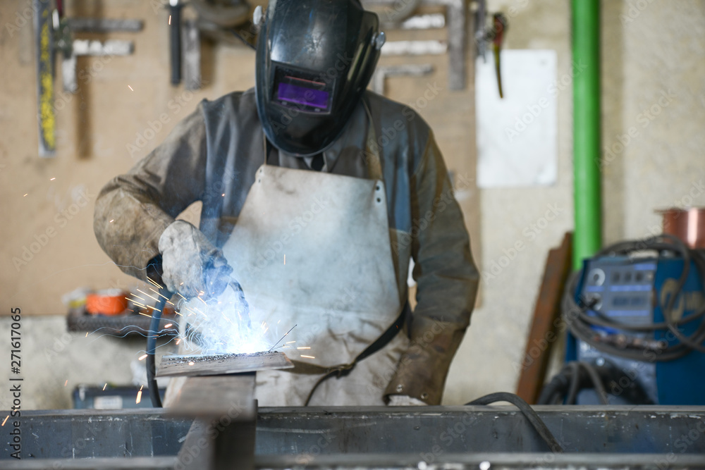 handsome man workshop welding iron spark fire hot steel with power GMAW welder and protective gear handsome man workshop welding iron spark fire hot steel with power GMAW welder and protective gear