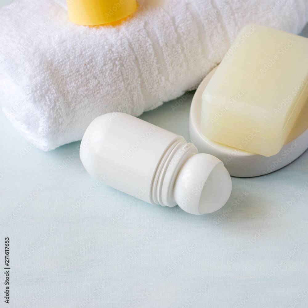 Body hygiene products. Roller deodorant, a piece of natural soap and a white terry towel on a light background with copy space. Selective focus. Body hygiene products. Roller deodorant, a piece of natural soap and a white terry towel on a light background with copy space. Selective focus.
