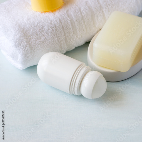 Body hygiene products. Roller deodorant, a piece of natural soap and a white terry towel on a light background with copy space. Selective focus.