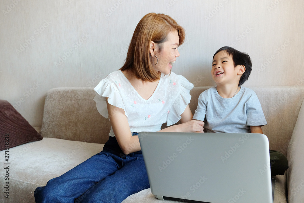 Asian Mother teaching her son for use laptop computer