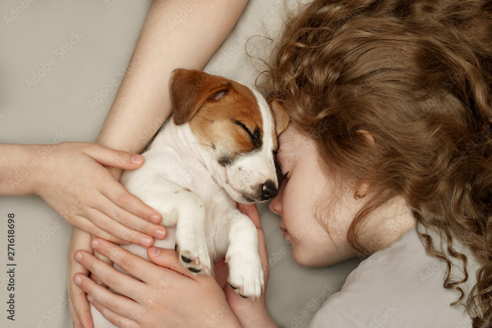 Curly girl and the children's hands hugging a puppy Curly girl and the children's hands hugging a puppy