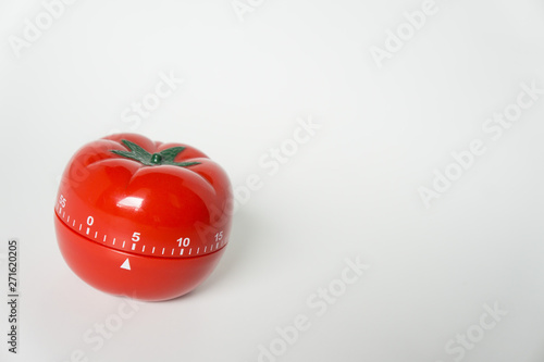 Close up view of mechanical tomato shaped kitchen clock timer for cooking & studying. Used for pomodoro technique for time and productivity management. Isolated on white background, set at 5 minutes.