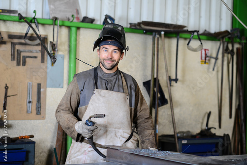 handsome man workshop welding iron spark fire hot steel with power GMAW welder and protective gear photo