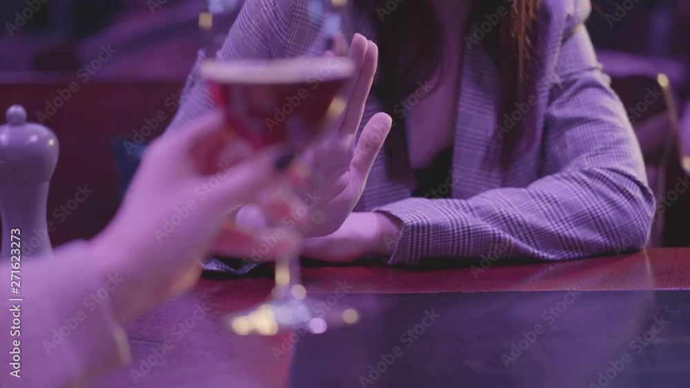 Female hand holding glass with alcohol cocktail close up. Unrecognizable woman making refusal gestures, she does not want to drink more alcohol. Unhealthy lifestyle Female hand holding glass with alcohol cocktail close up. Unrecognizable woman making refusal gestures, she does not want to drink more alcohol. Unhealthy lifestyle