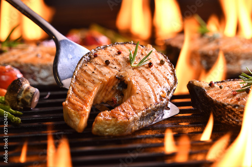 Foto Grilled salmon fish with various vegetables on the flaming grill