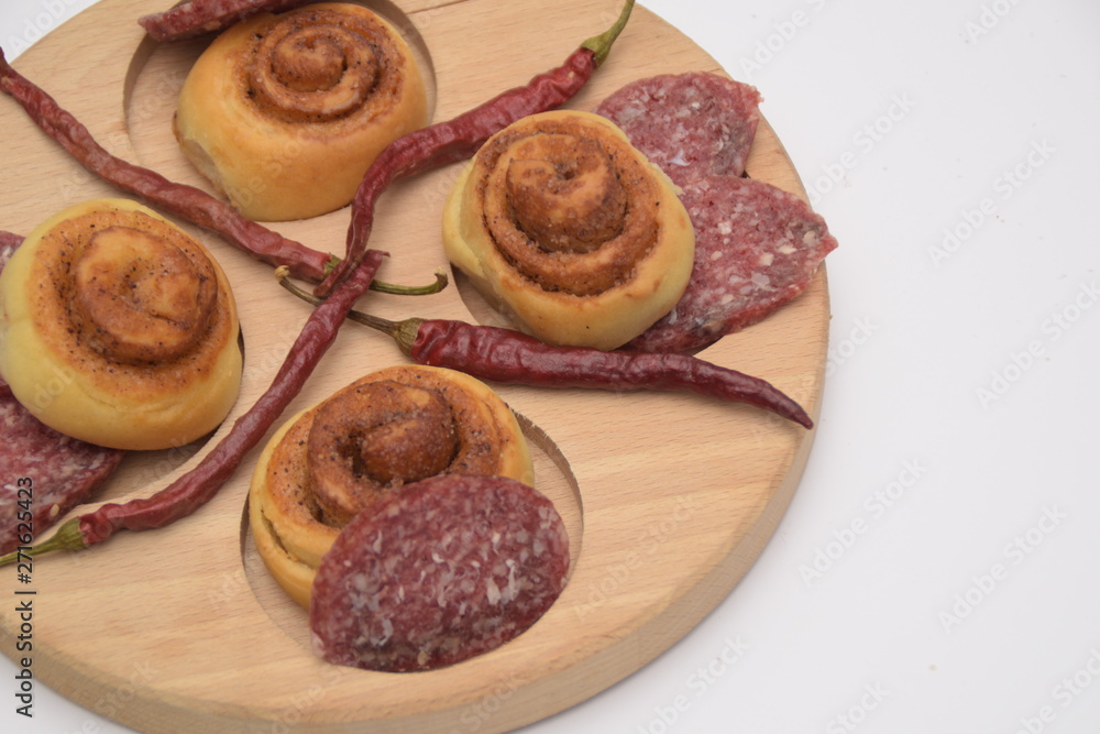 Salted dough. sliced sausage and chili peppers on a wooden board