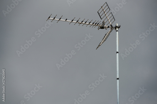 Telephoto lens of a television antenna on a roof with a grey sky background