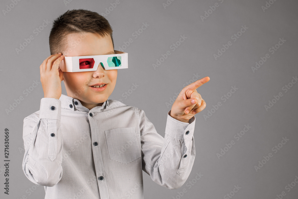 Young handsome boy with 3d glasses on grey background in Studio.