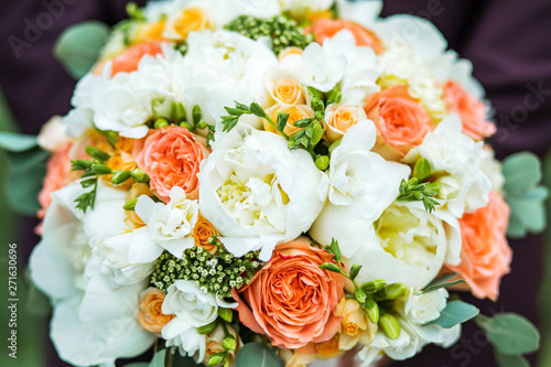 A beautiful bouquet of mixed flowers in the hand of the groom in a suit. Wedding bouquet of fresh flowers for the bride