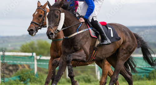 Close up on two horses and jockeys racing for position