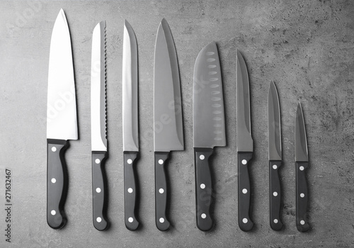 Set of sharp knives on grey background, flat lay