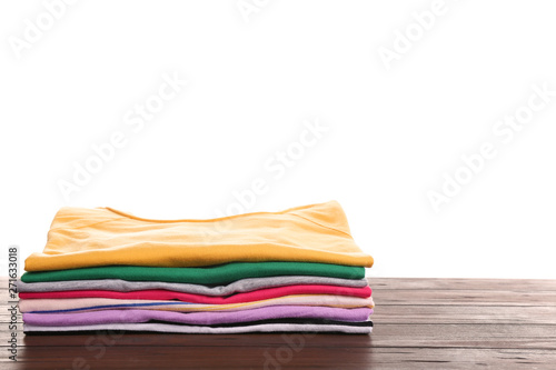 Pile of ironed clothes on table against white background. Space for text