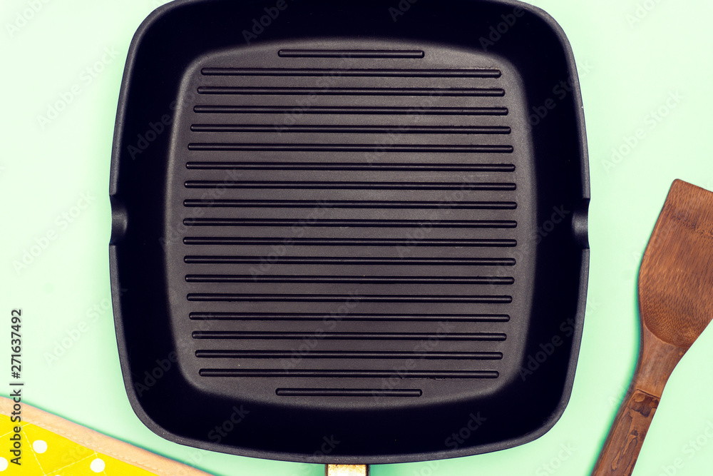 Empty grill pan on bright blue background. Grill food concept Empty grill pan on bright blue background. Grill food concept
