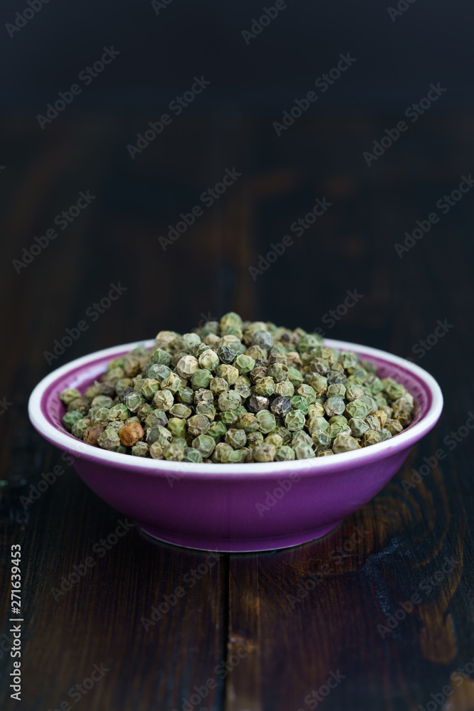 Dried green peppercorns in a violet bowl. Dark wooden table, high resolution, negative space Dried green peppercorns in a violet bowl. Dark wooden table, high resolution, negative space