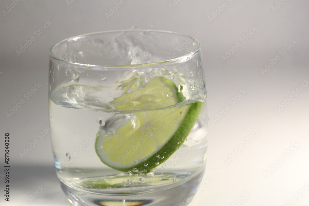 glass of water with green lime and splashes glass of water with green lime and splashes
