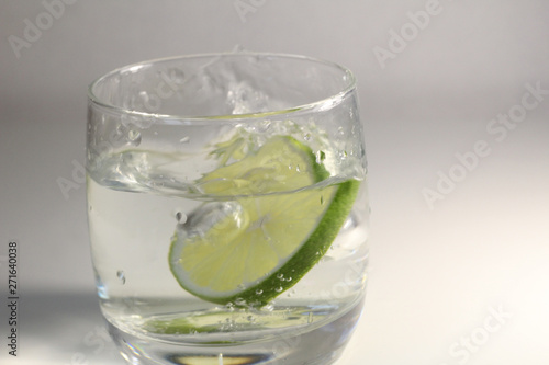 glass of water with green lime and splashes