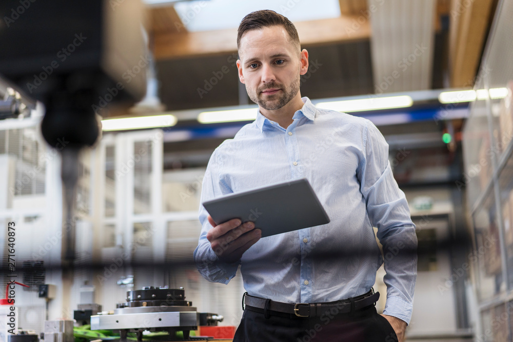 © Westend61 - Businessman using tablet at a machine in modern factory