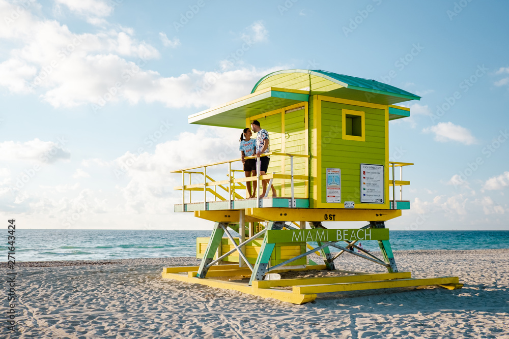 Fototapeta premium Miami South Beach, młoda para mężczyzn i kobiet na plaży podczas wschodu słońca. Miami Beach Floarida