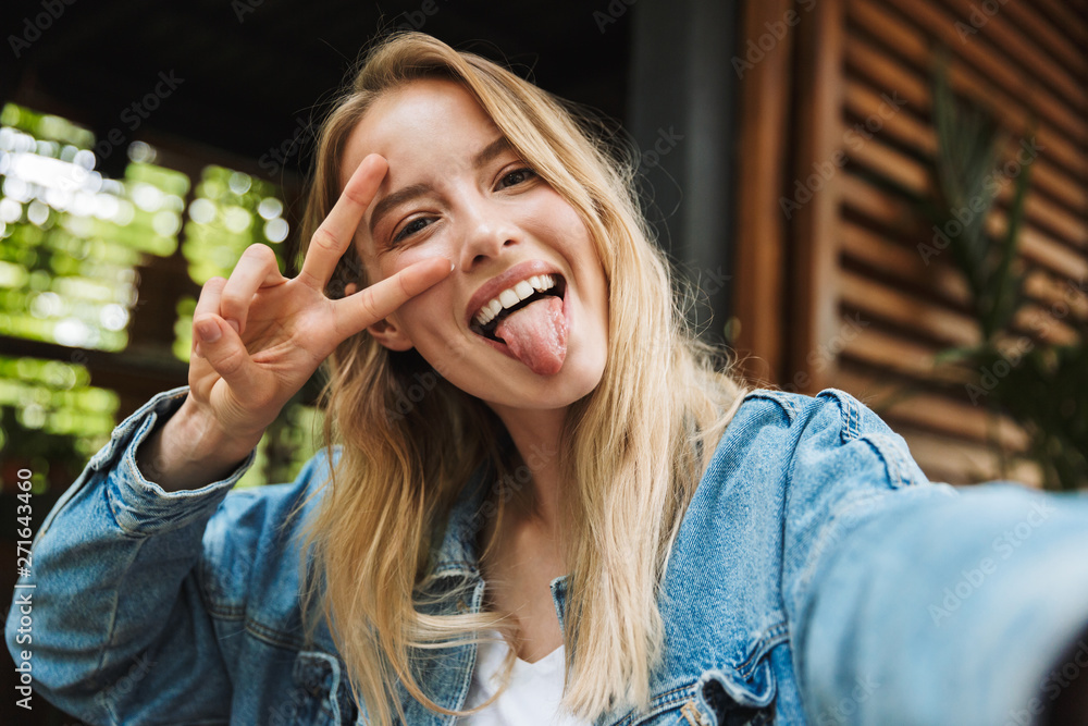 Fototapeta premium Amazing excited happy young woman posing outdoors in cafe take a selfie by camera.
