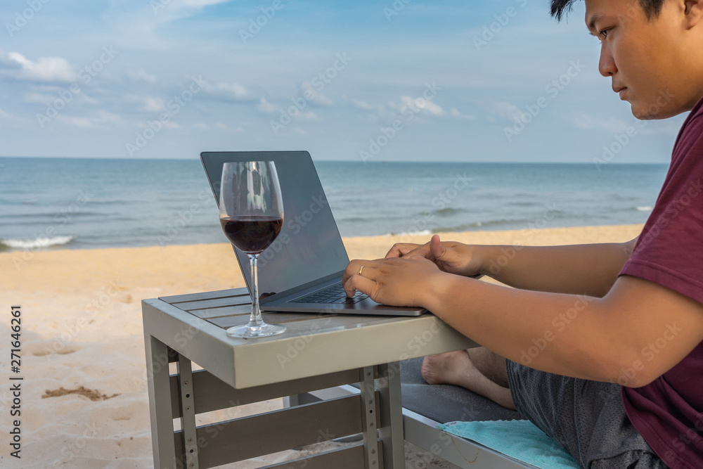 Asian freelancer working on laptop in front of beautiful beach
