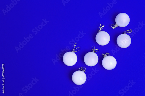 White Christmas balls ornaments on bright blue background. Flat lay New Year minimal decoration. Christmas card. Top view.