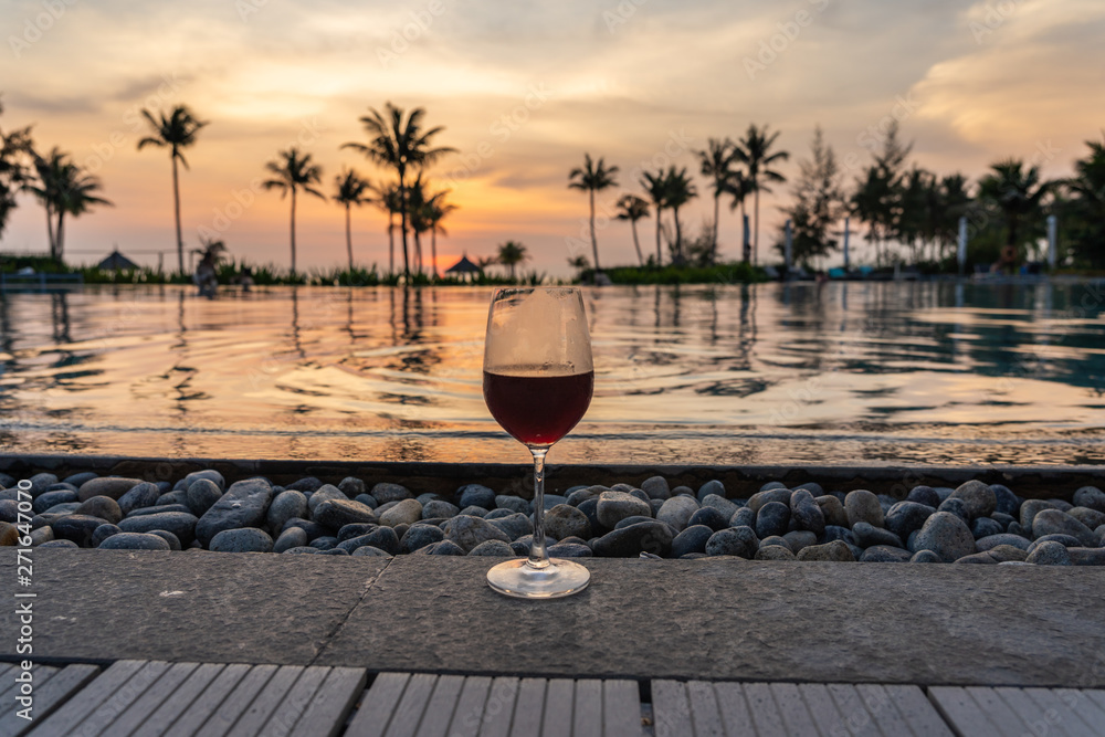 Glass of red wine with the swimming pool background