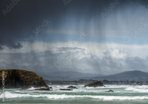 Rain showers blown by the wind between the sea and the cliffs