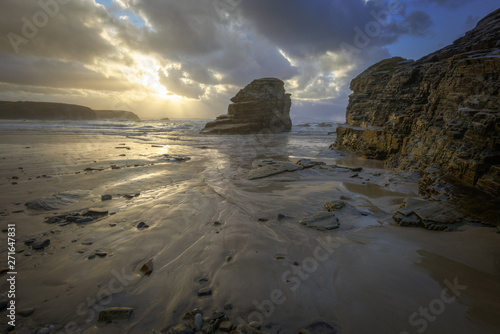 Sun rays of sunset seeps through the clouds on a beach