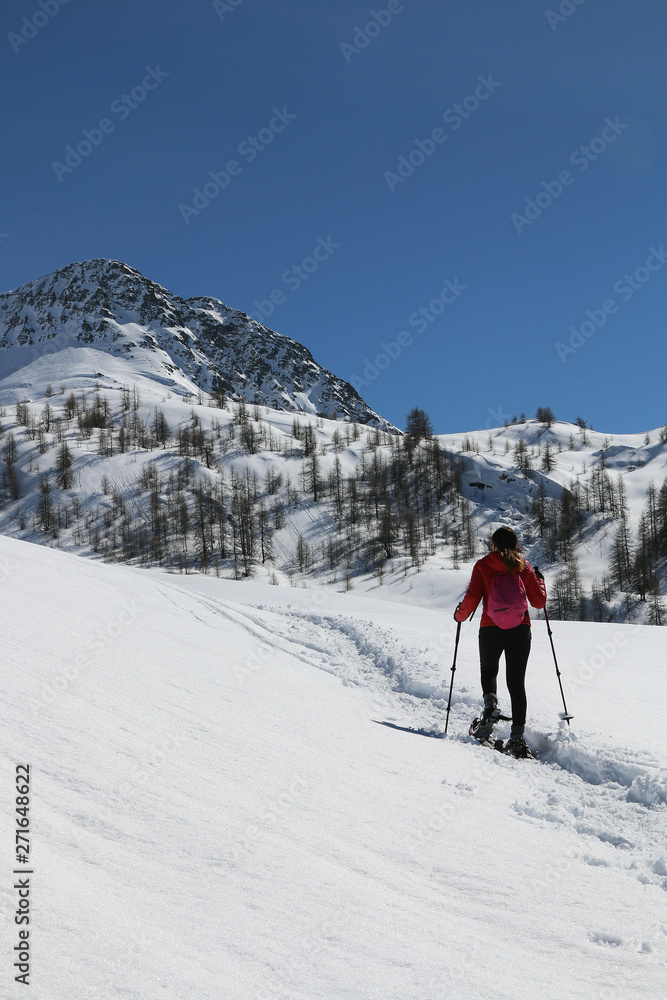 Winter sport activity, woman hiking with snowshoes on snow trail on italian alps, Valle d'Aosta.
