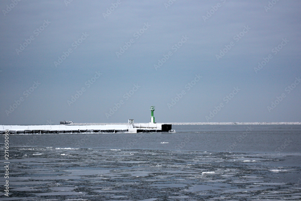 winter port, snowed breakwater and green lighthouse