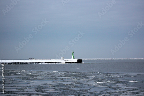 winter port, snowed breakwater and green lighthouse