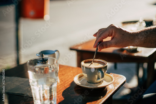 male hand stirring coffee at a coffee shop