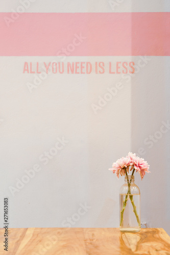 Natural fresh pretty flowers in glass bottle on wooden table with all you need is less text on background