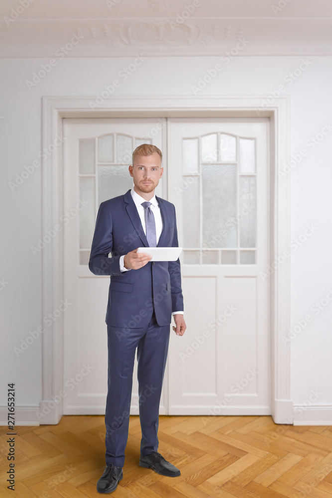 Real estate agent or interior designer in suit and tie in front of a white double door in historic building. Real estate agent or interior designer in suit and tie in front of a white double door in historic building.