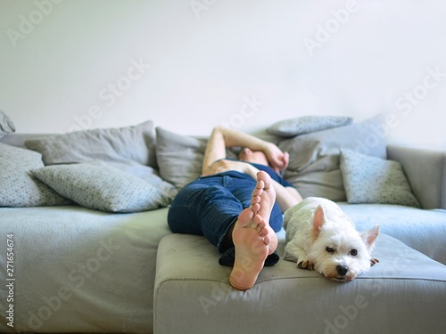 adult woman lying on sofa with white dog