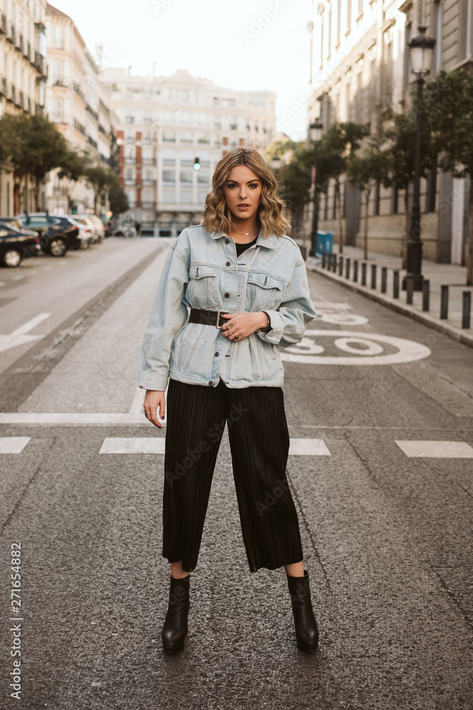 Beautiful female in trendy outfit standing in middle of asphalt road on city street Beautiful female in trendy outfit standing in middle of asphalt road on city street