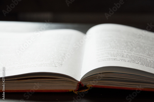 An open book is on the table. On a dark background. Close-up
