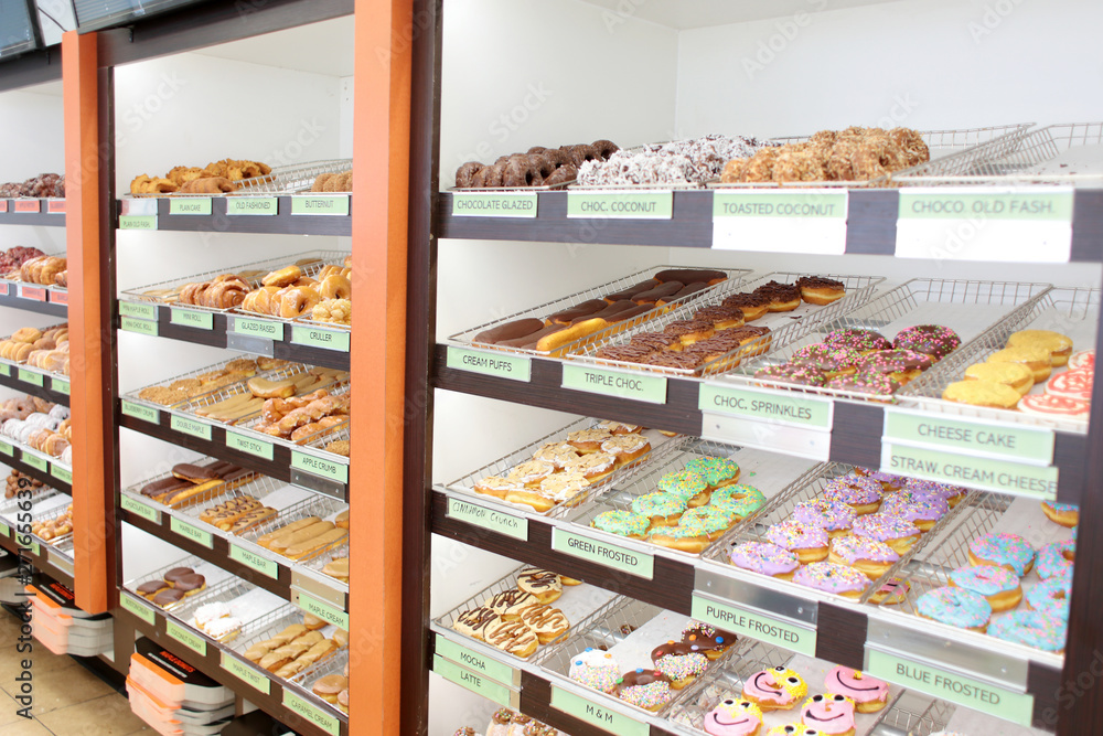 Assorted fresh donuts on display racks at the donut shop.