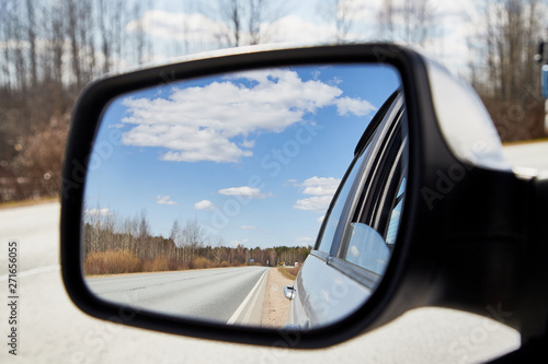 Side view mirror reflection of landscape with road and sky with clouds in sunny spring or autumn day © keleny