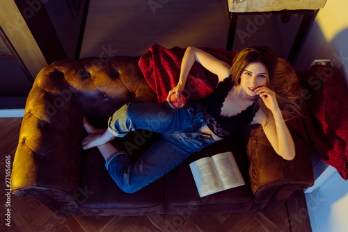 Young sexy woman sitting on sofa with apple