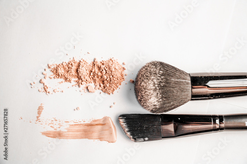powder slide, a touch of foundation and two black makeup brushes photo