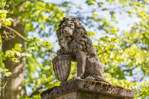 Stone statue of bavarian lion, holding a shield with the diamond pattern of the bavarian flag. The statue guards the entrance of an estate in upper bavaria.