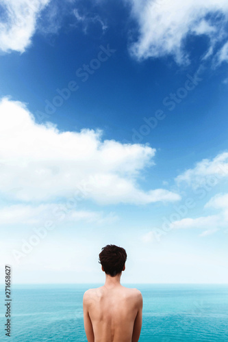 slim girl with a beautiful bare back is standing on the sea. Blue sky with clouds. Unity with nature. freedom. Life