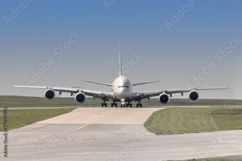 front view of a four engine big jet plane waiting on a taxiway for taking off permission. photo