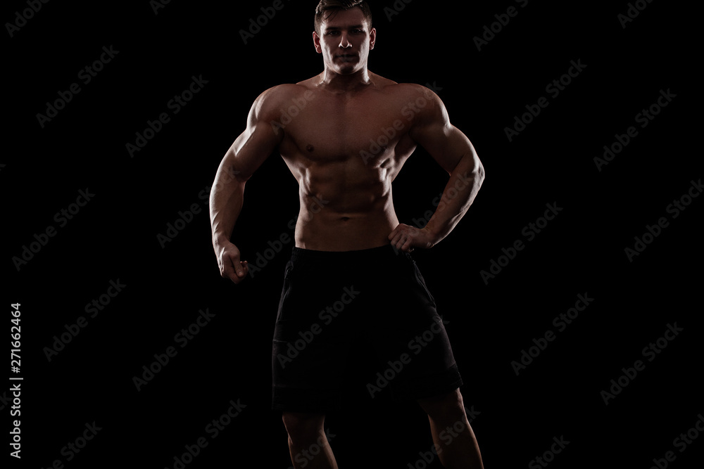 Obraz premium Bodybuilding competitions on the scene. Man sportsmen physique and athlete. Black background with lights.
