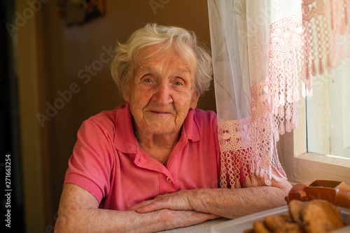 Portrait of a senior woman with deep wrinkles. Smiling grandmother looks to the camera.