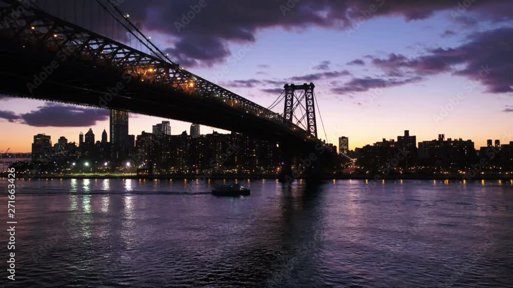 Boat passes under Williamsburg Bridge at night, aerial