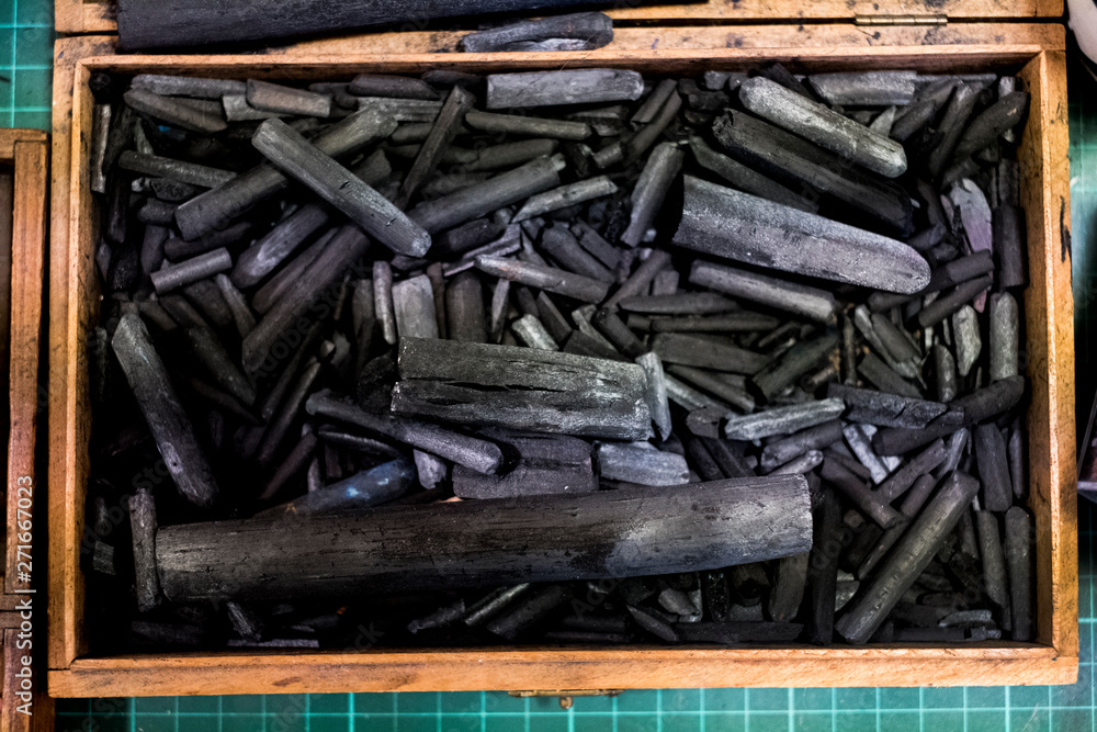 High angle close up of wooden box with a selection of artist's charcoal sticks in different sizes. High angle close up of wooden box with a selection of artist's charcoal sticks in different sizes.
