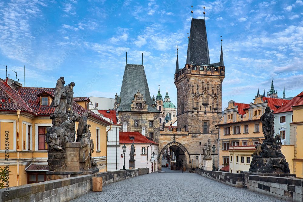 Morning at Charles Bridge in Prague, Czech Republic. Solitary road with statues and paving stones. Antique medieval tower and arch of entrance to the old town Mala Strana district downtown. Morning at Charles Bridge in Prague, Czech Republic. Solitary road with statues and paving stones. Antique medieval tower and arch of entrance to the old town Mala Strana district downtown.