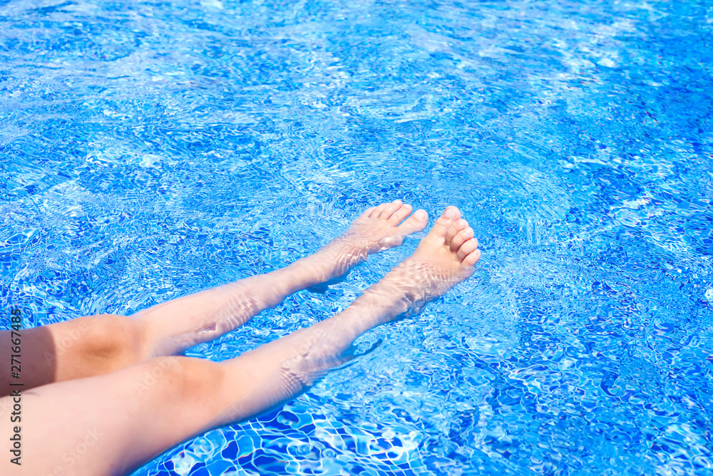 Feet of little girl moving under the water in the pool. Summer. Funny underwater legs in swimming pool, vacation and sport concept.